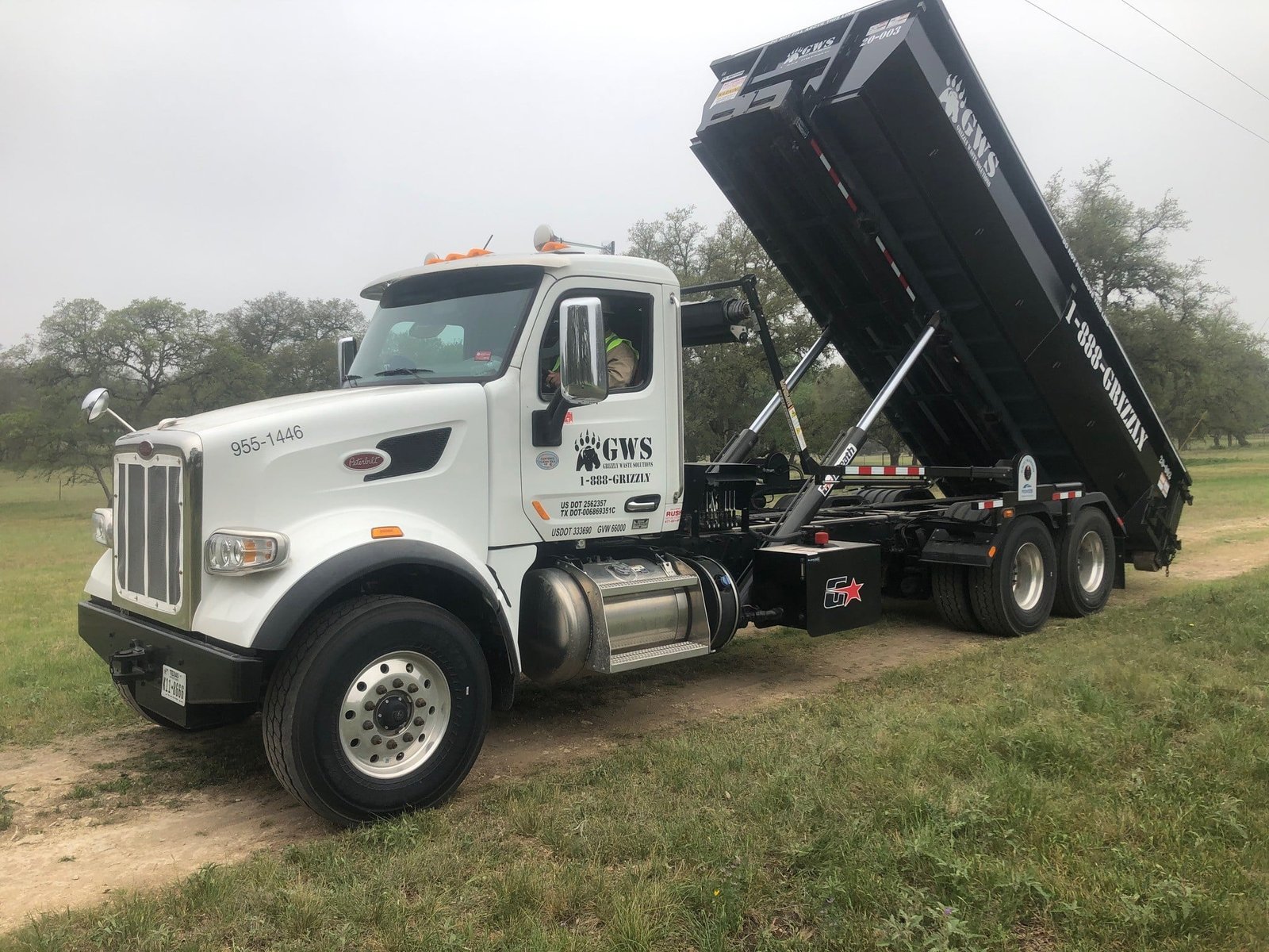 grizzly waste solutions truck with a dumpster rental san antonio offloading the truck